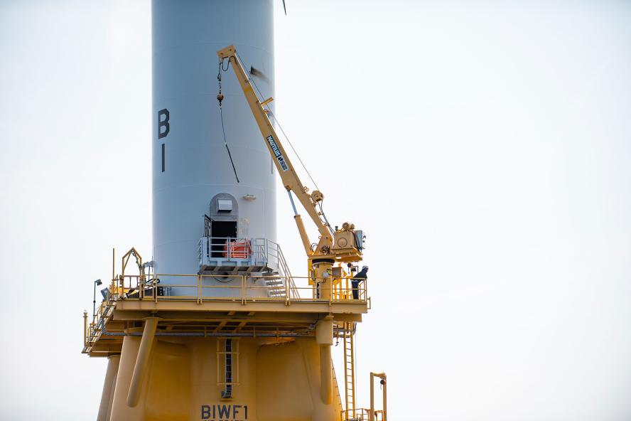 Worker standing at offshore wind turbine tower entrance