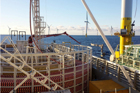 A cable-laying vessel lays cable at sea in a wind farm